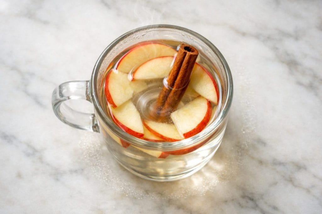 Ρόφημα μήλου κανέλα με ινοσιτόλη σε γυάλινη κούπα, με φέτες μήλου και ξυλάκι κανέλας.